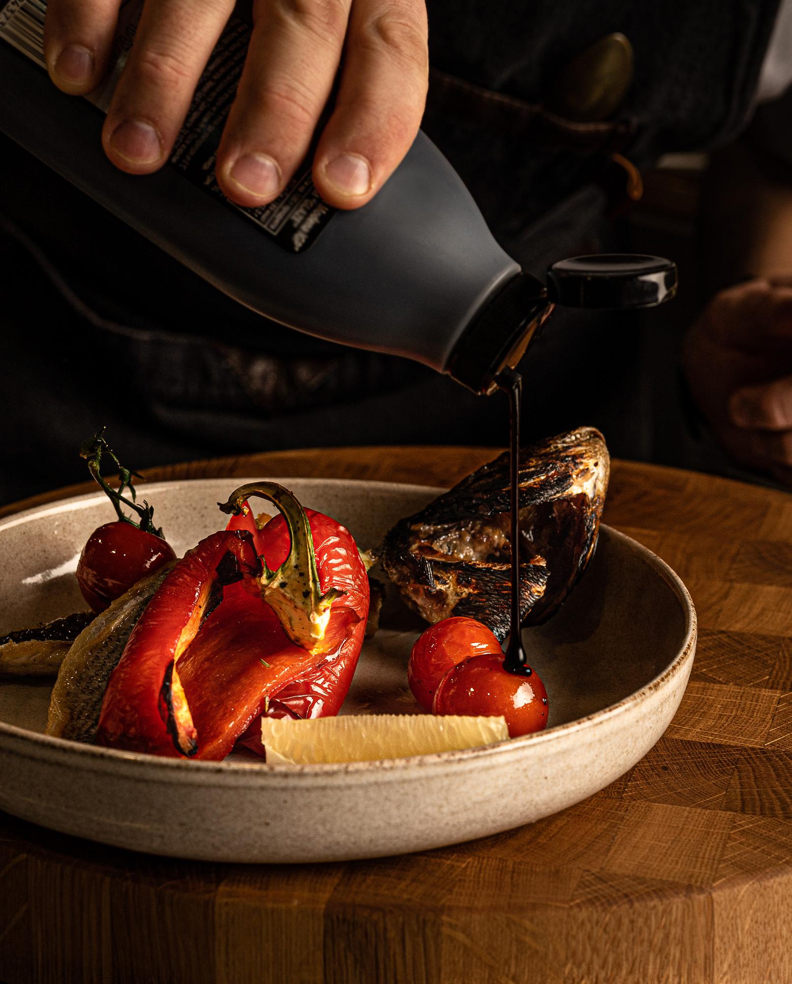 Chef arranges plated dish on wooden table